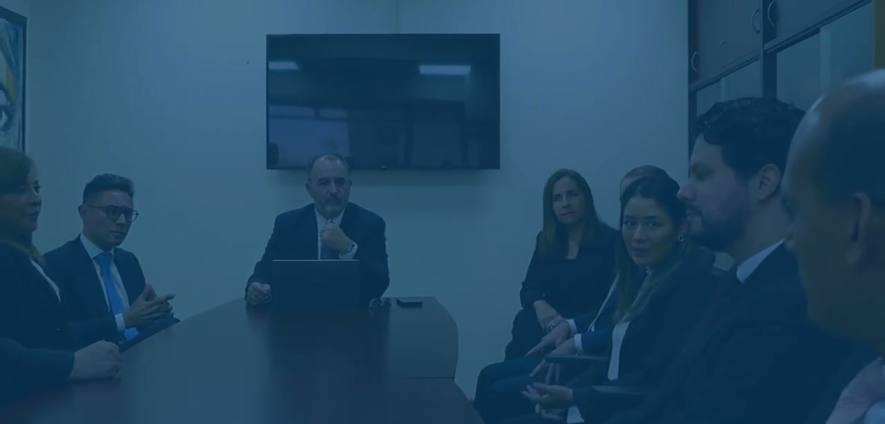 Reunión de trabajo alrededor de una mesa, con una pantalla al fondo